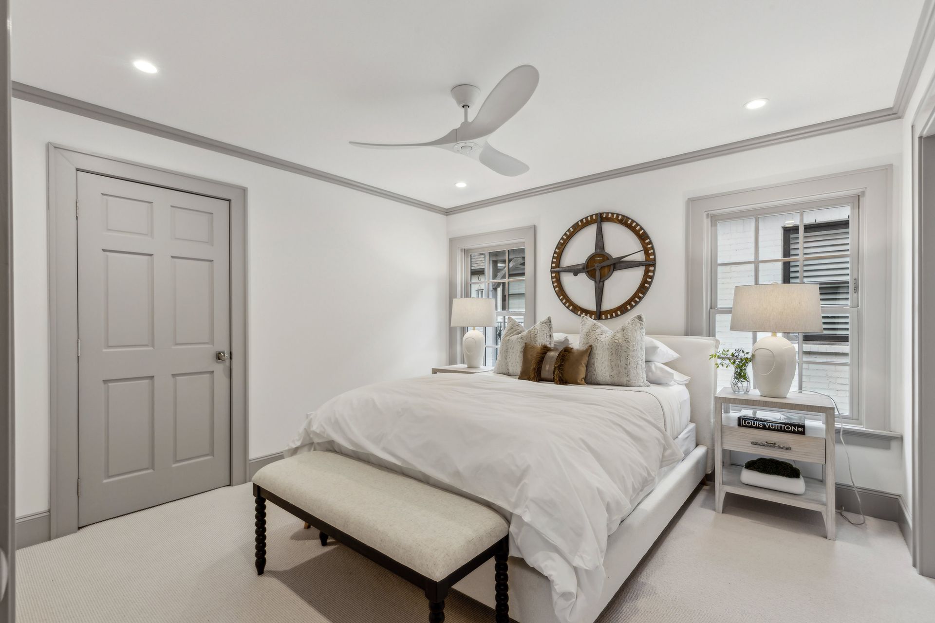 White bedroom with gray trim, bed, nightstands, and a decorative wall clock.