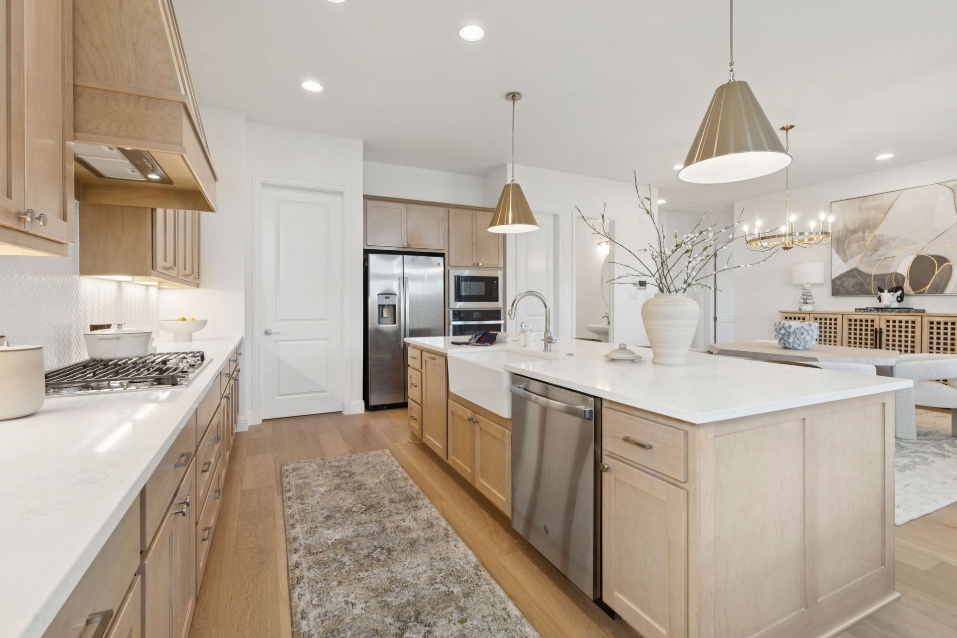 Modern kitchen with light wood cabinets, stainless steel appliances, and a large island.