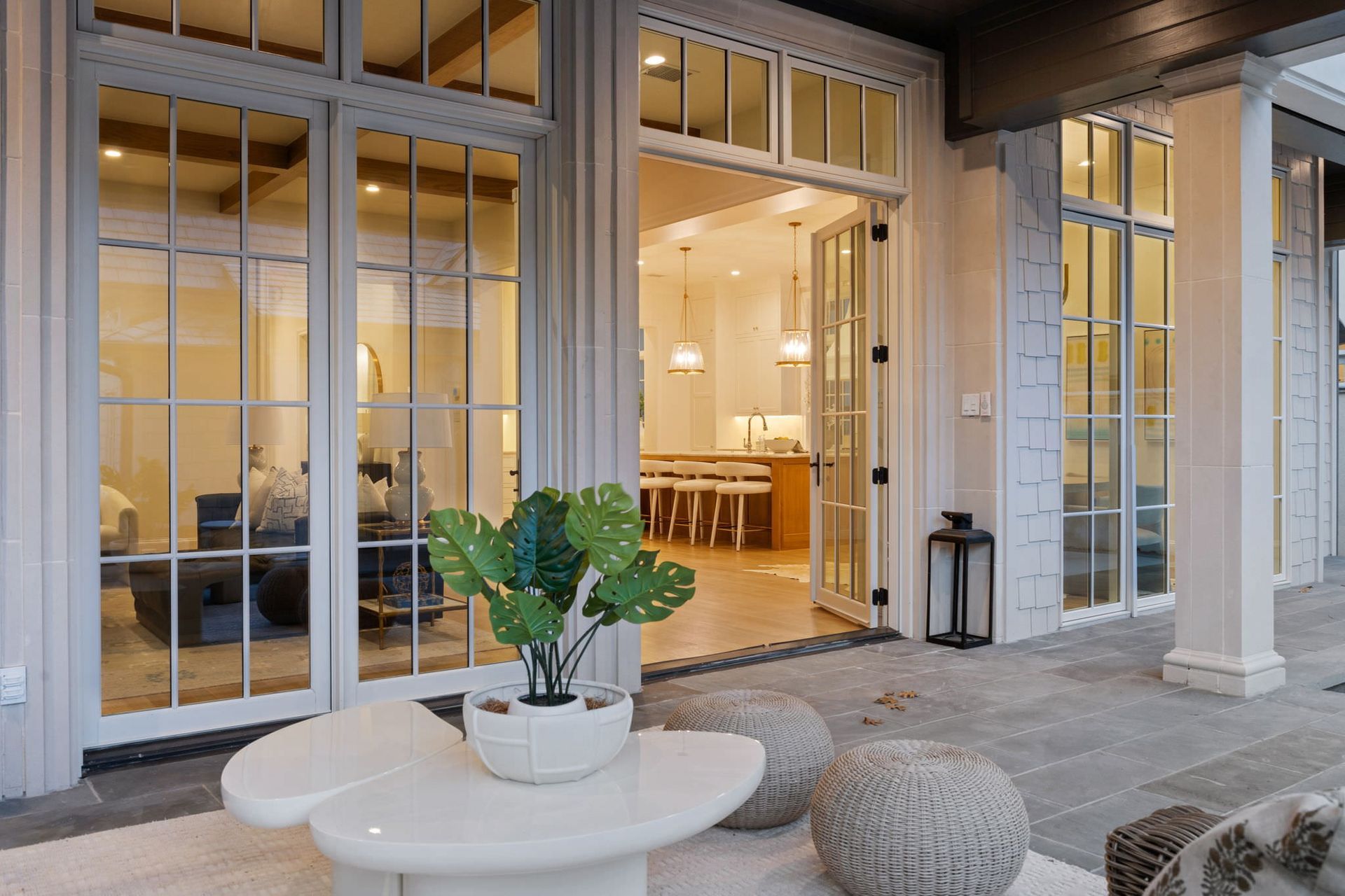There is a table with a plant on it in front of a large window.