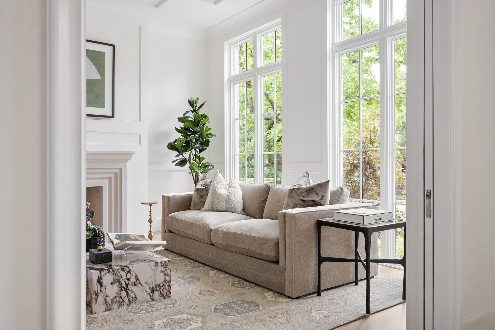 A living room with a couch , coffee table , fireplace and lots of windows.