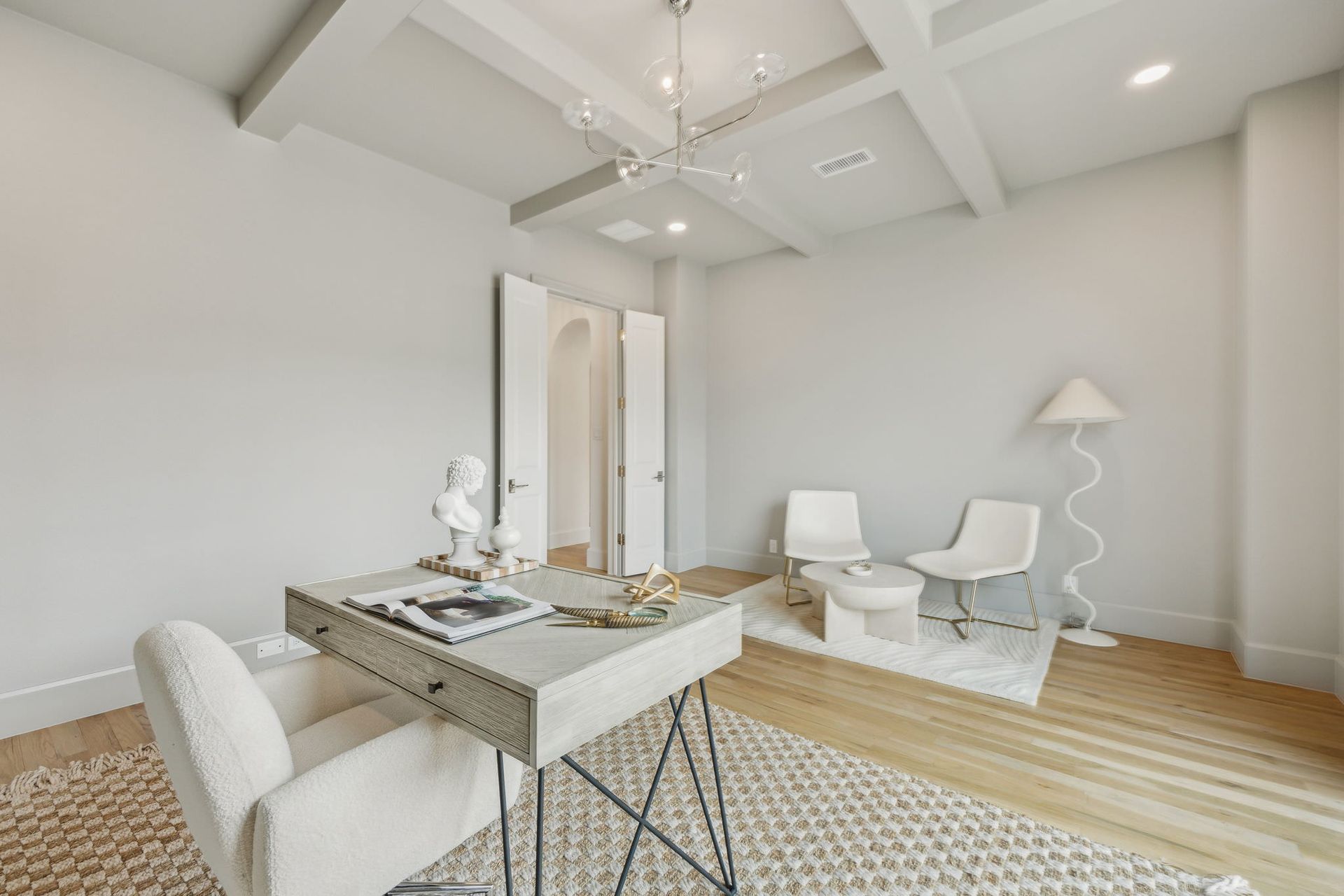 A light-filled office with a desk, chairs, and a rug. White walls and wood floors.