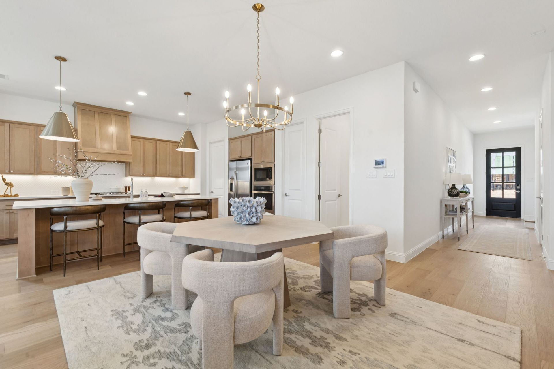 Open-concept kitchen and dining area with light wood cabinets, a table, and a rug.