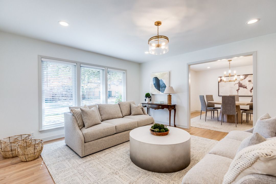 A living room with a couch , coffee table and dining room in the background.