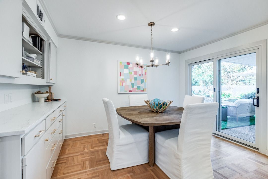 A dining room with a wooden table and white chairs.