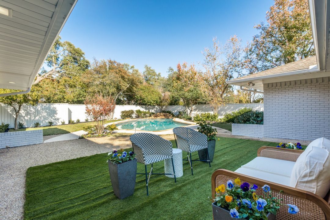 A backyard with a couch , chairs , and a pool.