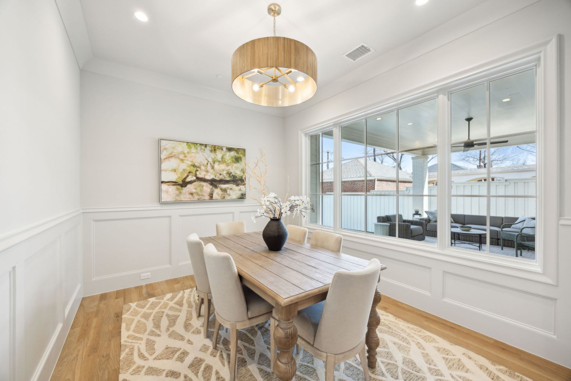 Dining room with a wooden table, chairs, and a large window overlooking a patio.