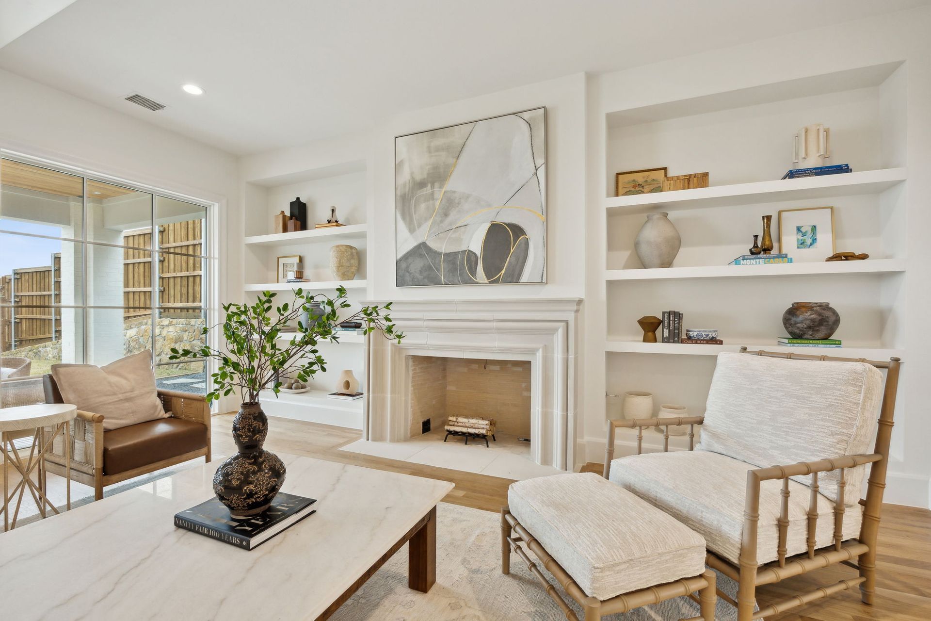 Living room with fireplace, built-in shelves, artwork, and seating in a bright, modern space.
