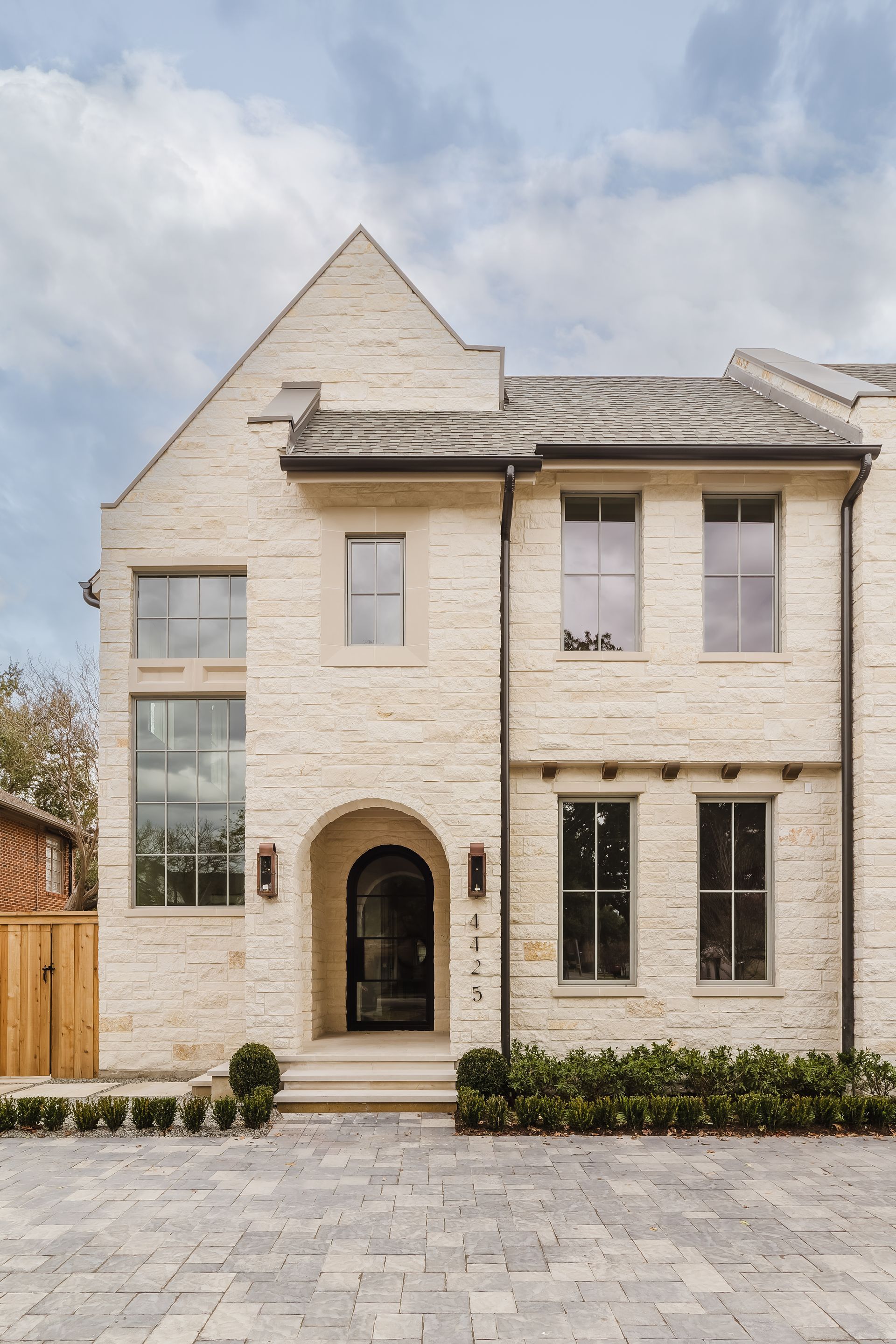 A large white brick house with a lot of windows and a black door.