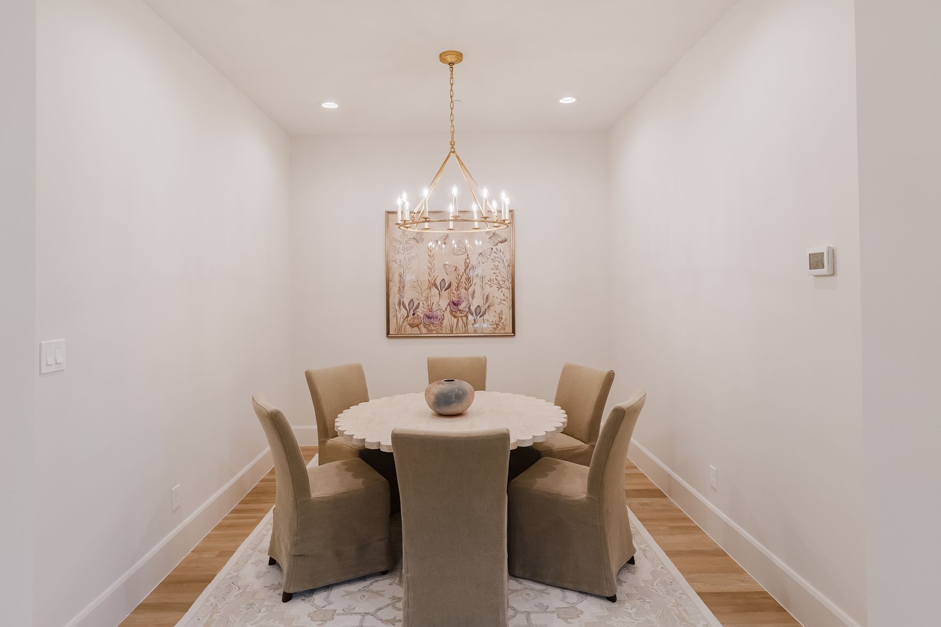 A dining room with a round table and chairs and a chandelier.