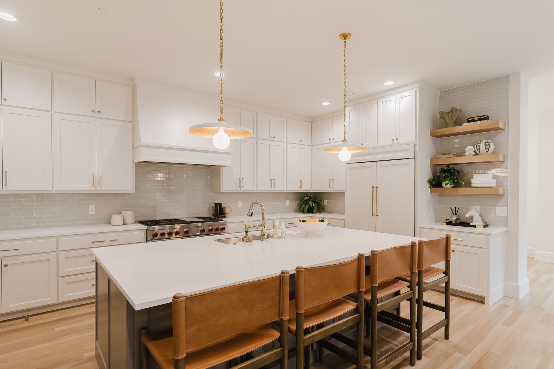 A kitchen with white cabinets , a large island , and brown chairs.