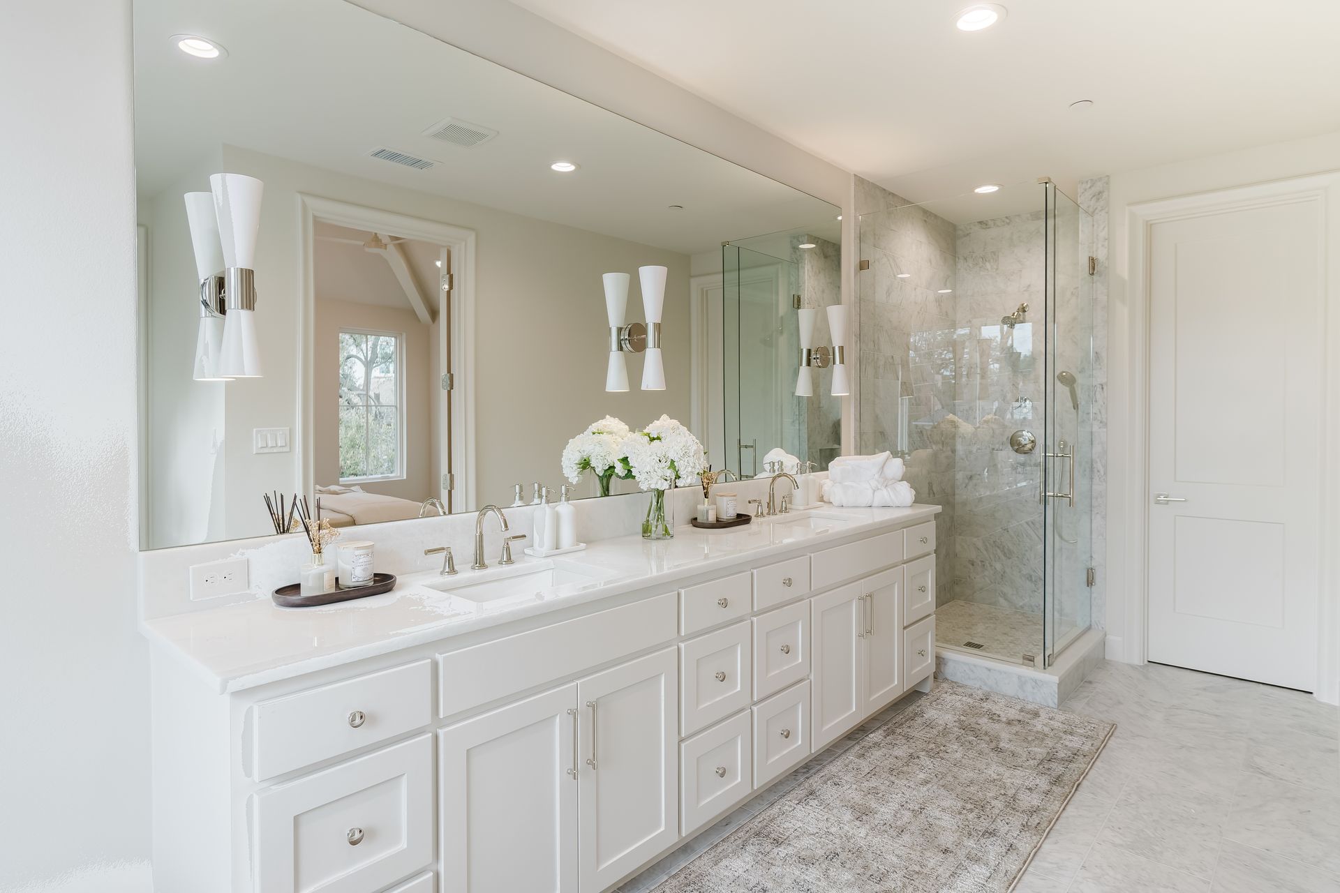 A bathroom with two sinks , a walk in shower and a large mirror.