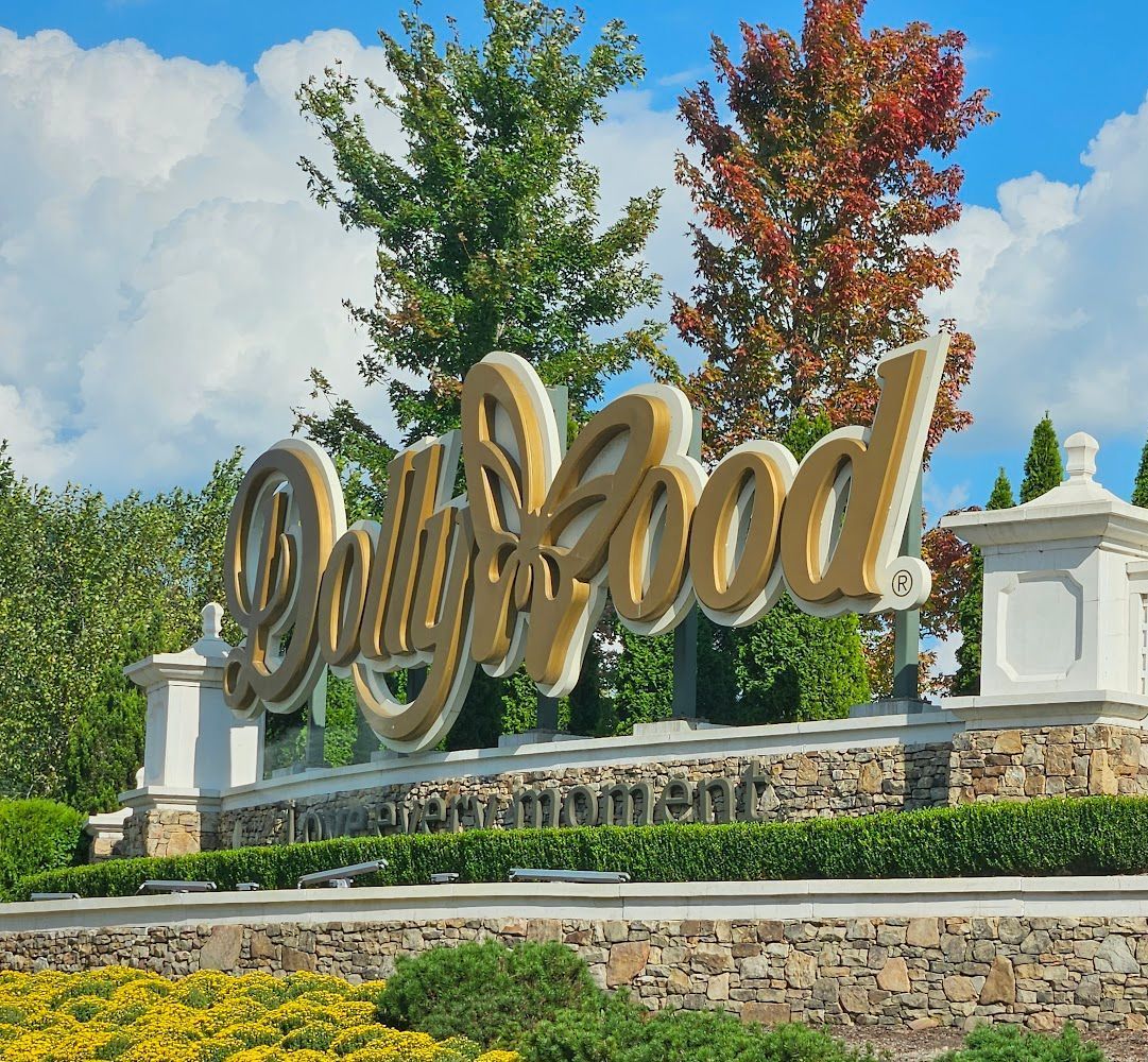A sign for dolly wood is surrounded by trees and bushes