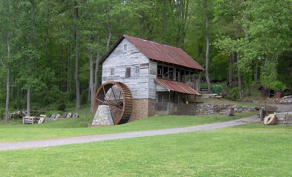 A small house with a water wheel in front of it.