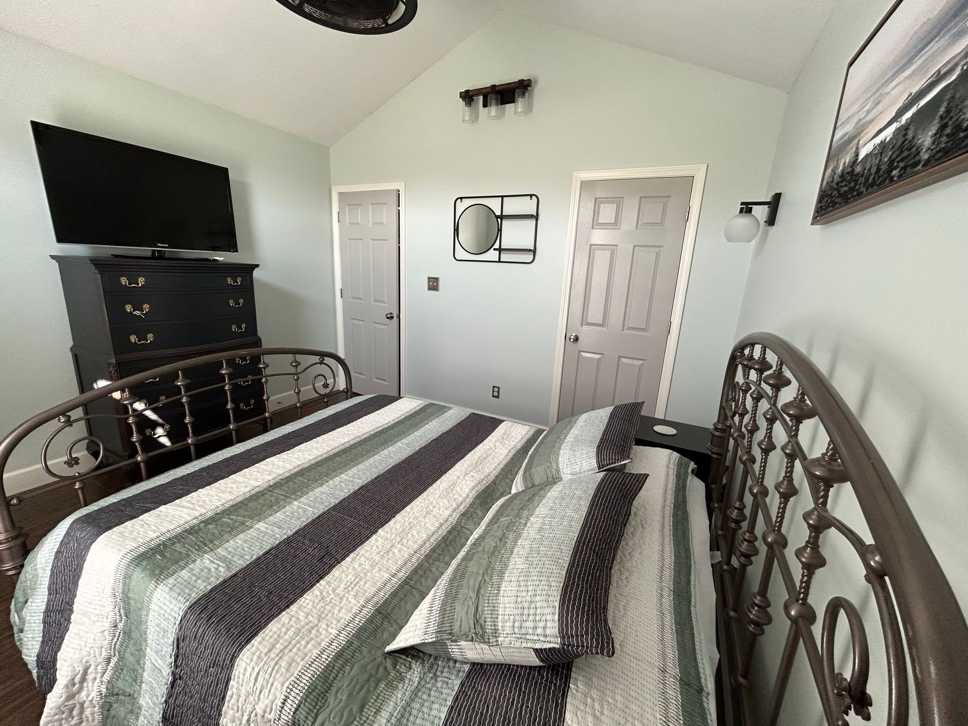 A bedroom with a bed , dresser and television.