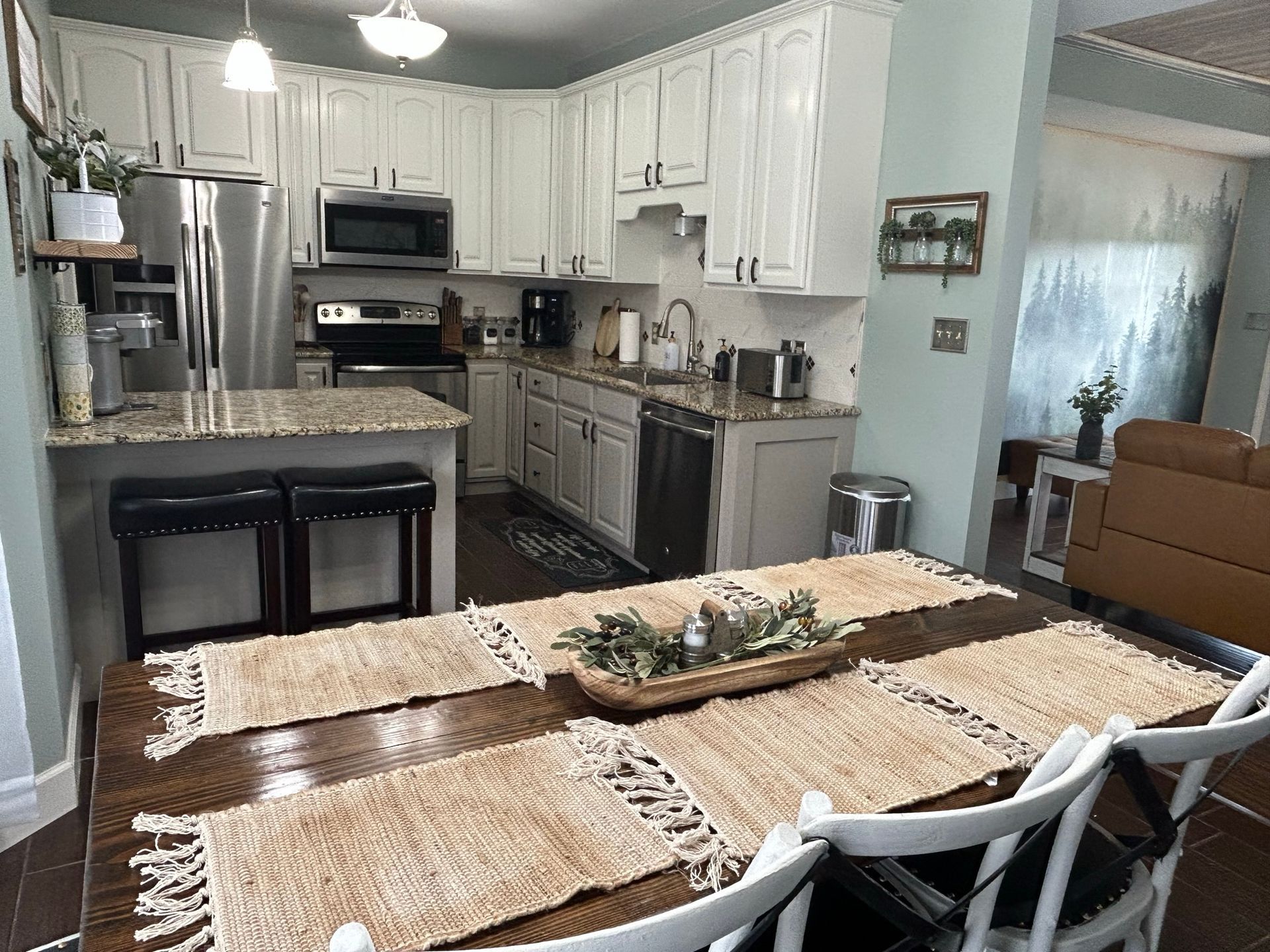 A kitchen with white cabinets , stainless steel appliances , a table and chairs.