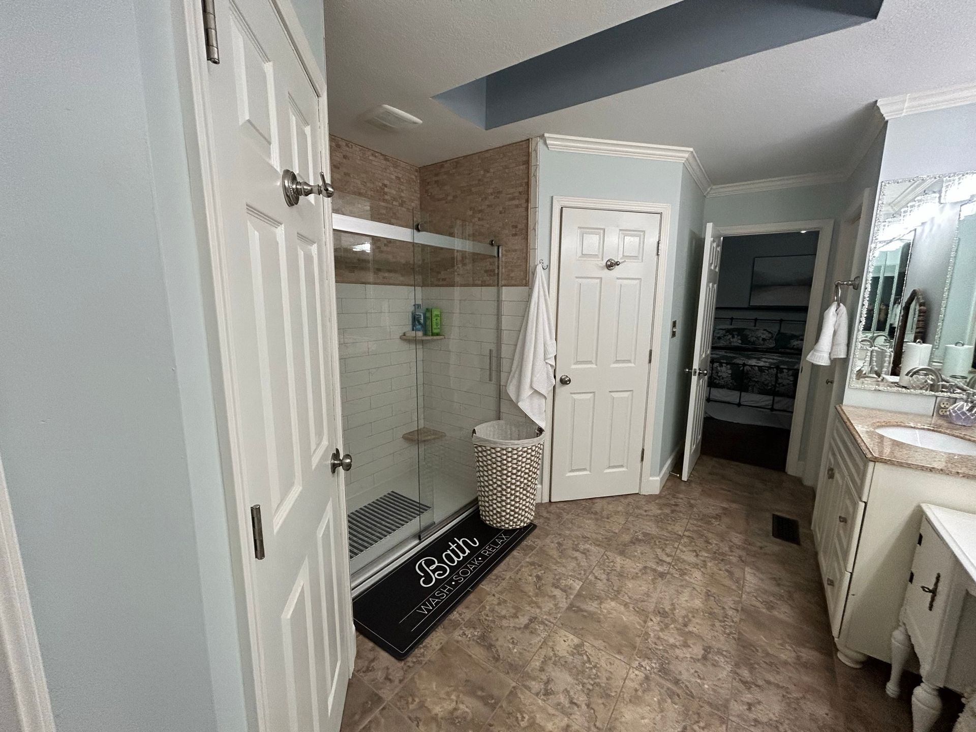 A bathroom with a walk in shower , sink , and mirror.