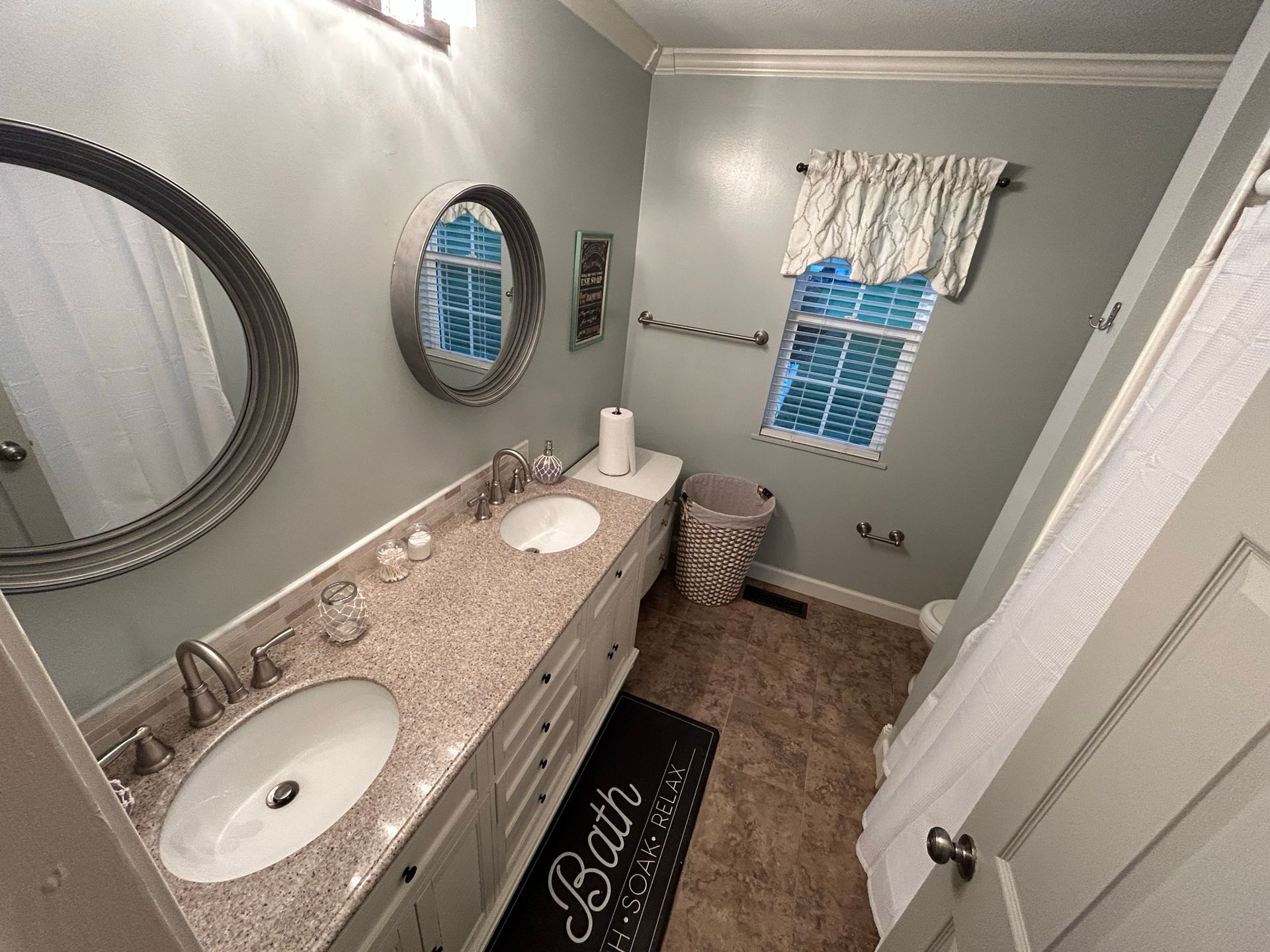 A bathroom with two sinks , a mirror and a rug.