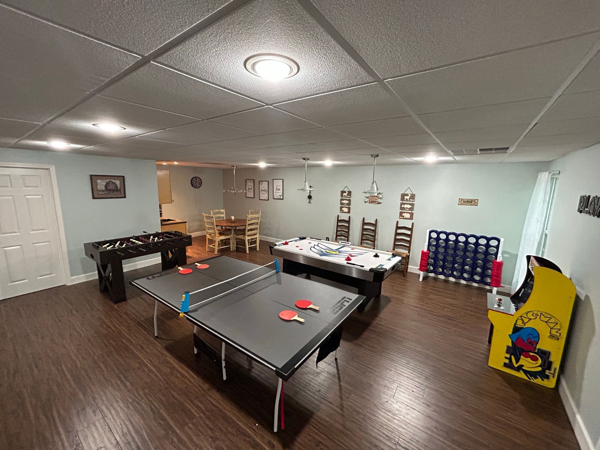 A game room with ping pong tables , a foosball table ,air hockey and an arcade machine