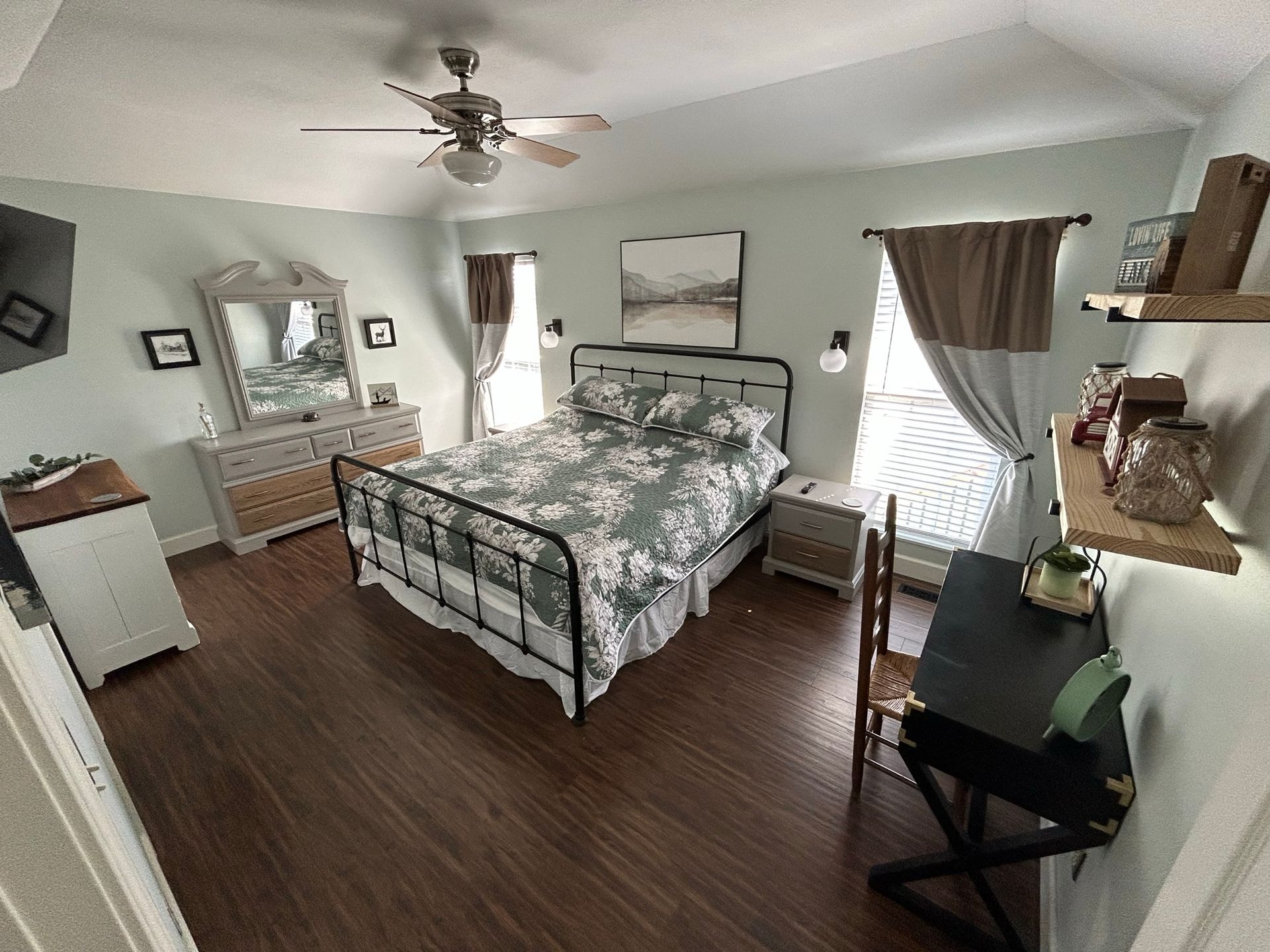 A bedroom with a bed , dresser , desk and ceiling fan.