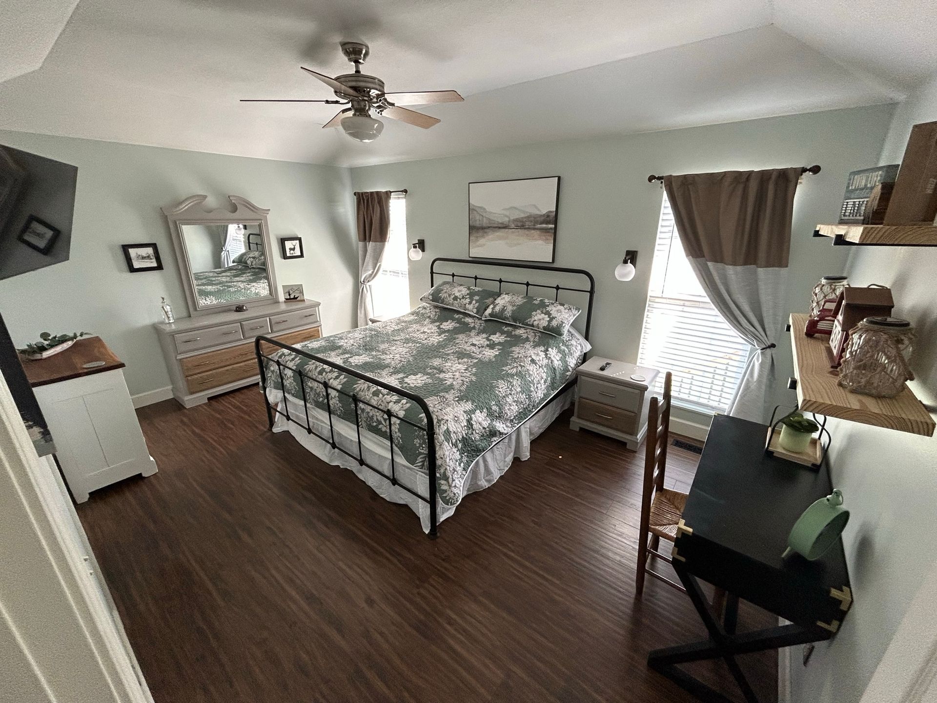 A bedroom with a bed , dresser , mirror and ceiling fan.