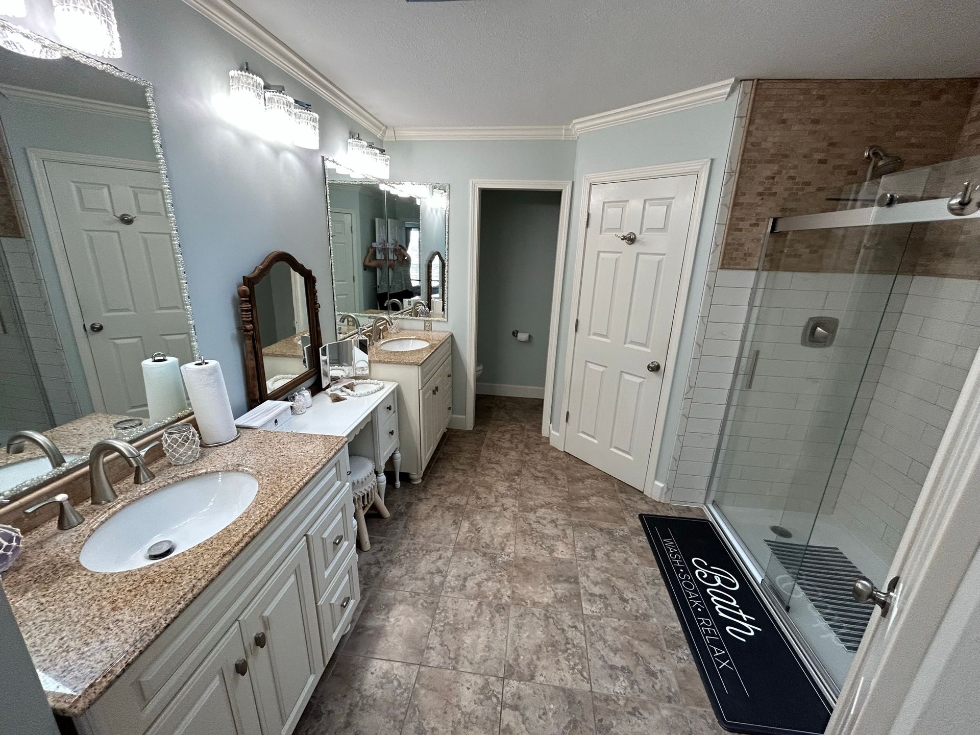 A bathroom with two sinks , a mirror and a walk in shower.