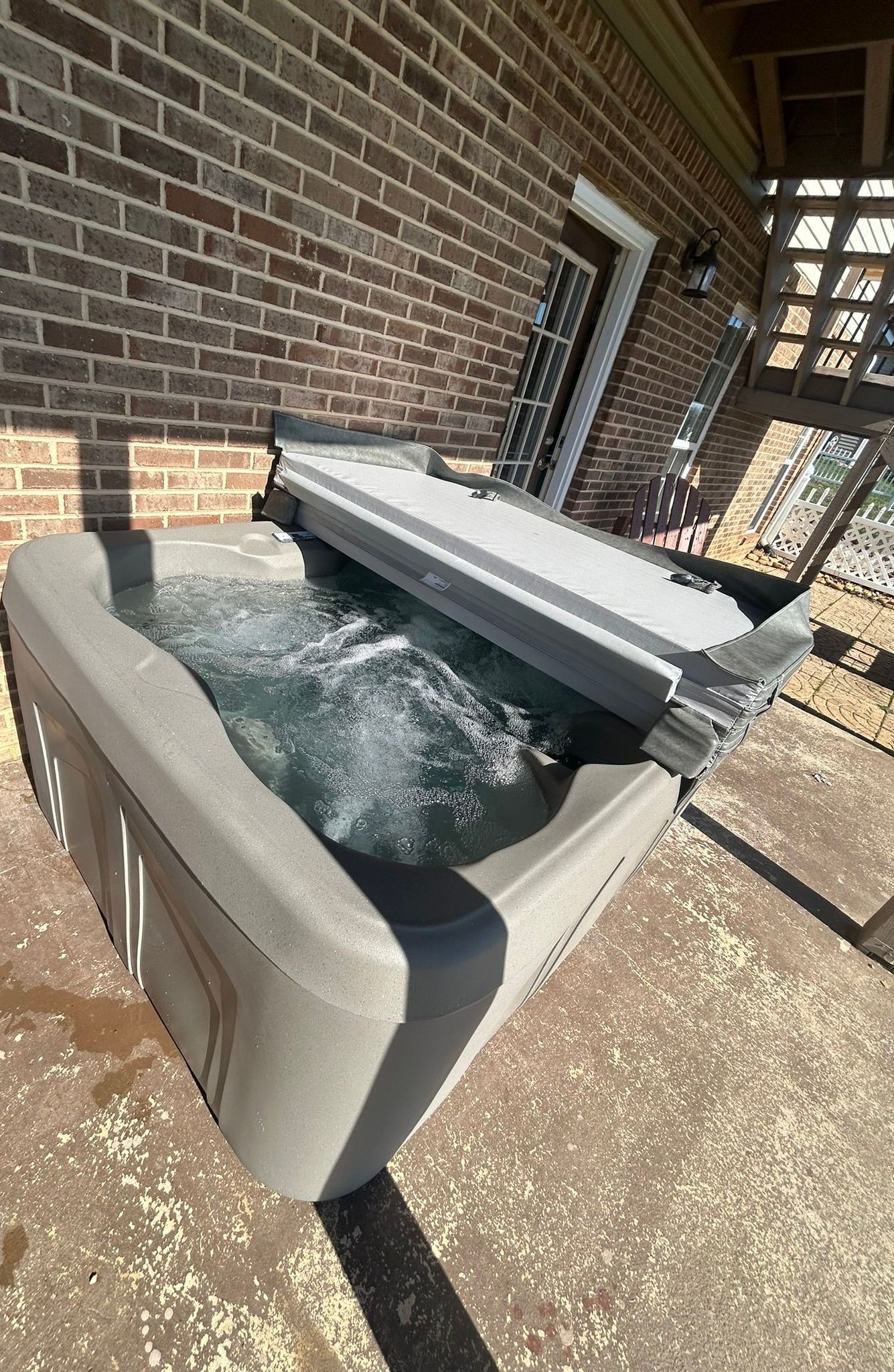 A hot tub is sitting outside of a brick building.