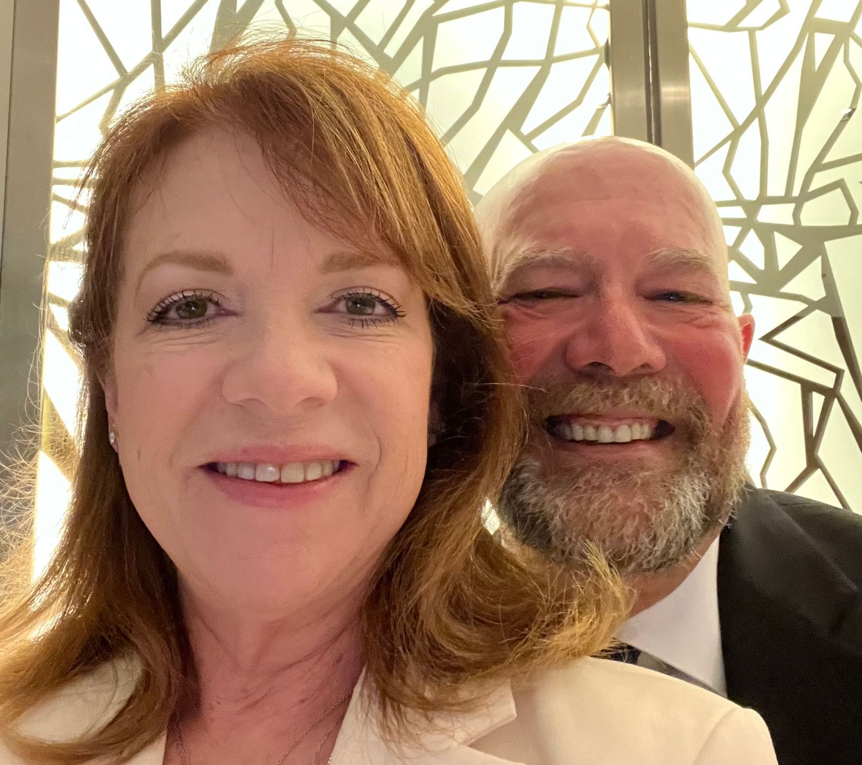 A man and a woman are posing for a picture and smiling