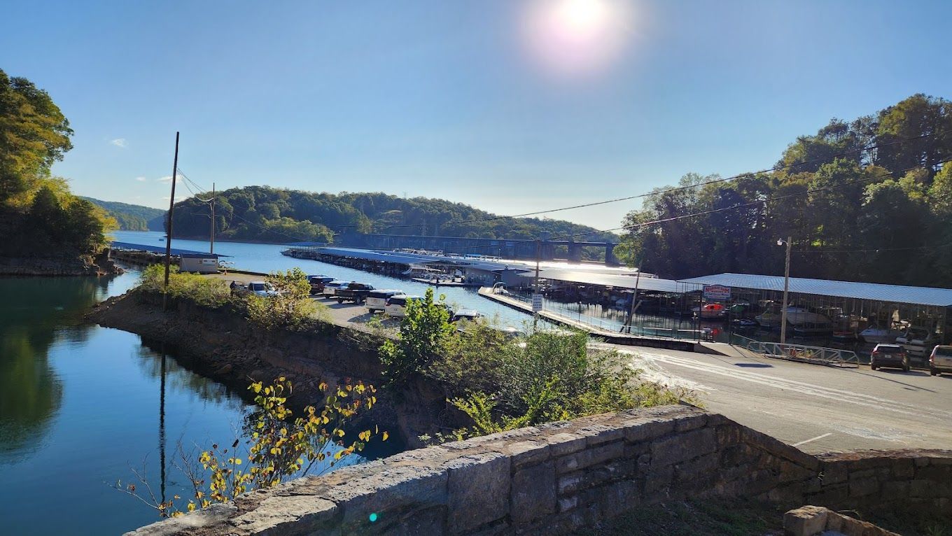 A large body of water surrounded by trees and a road.