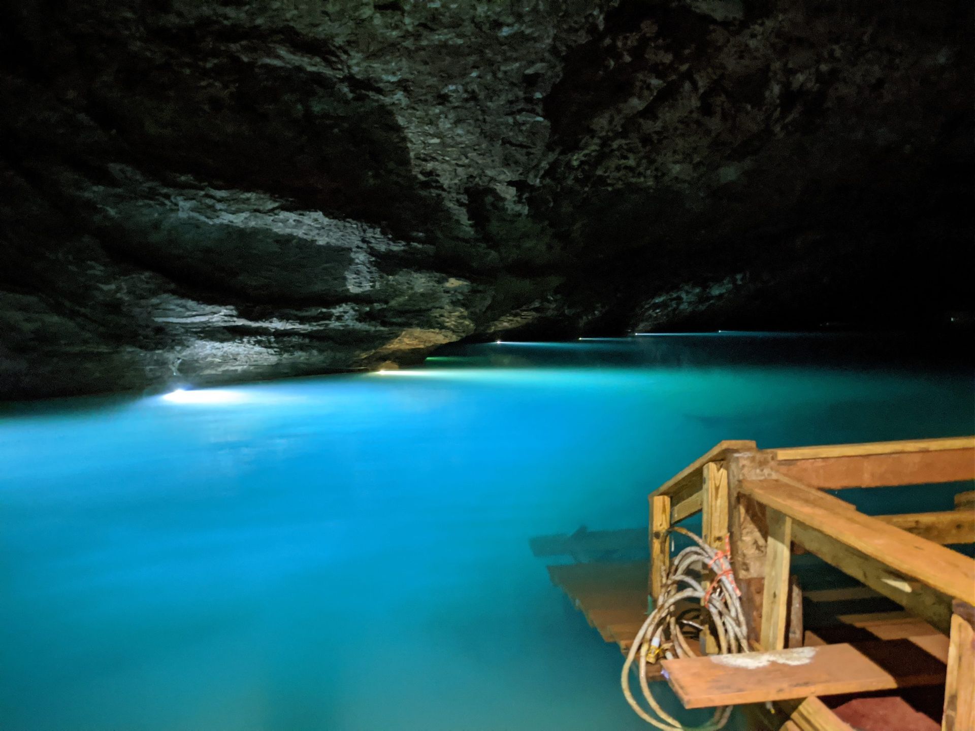 A wooden dock in a cave with blue water
