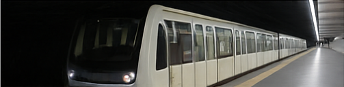 Un treno della metropolitana entra in una stazione. Una carrozza bianca con molti finestrini su una banchina.