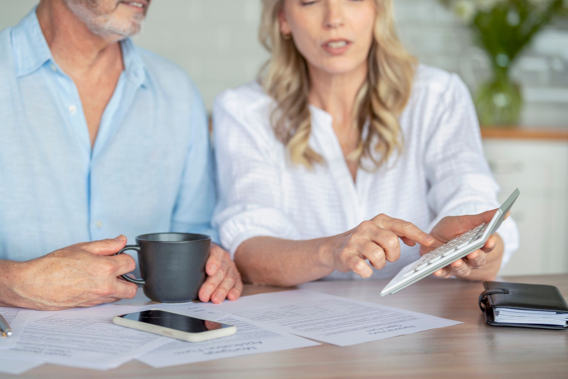 A man and a woman are sitting at a table looking at a tablet.