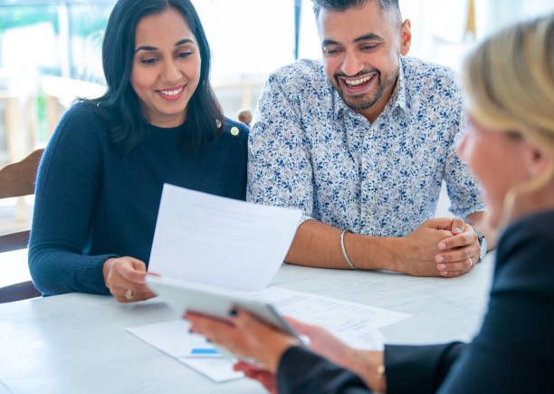 A man and a woman are sitting at a table looking at a piece of paper.