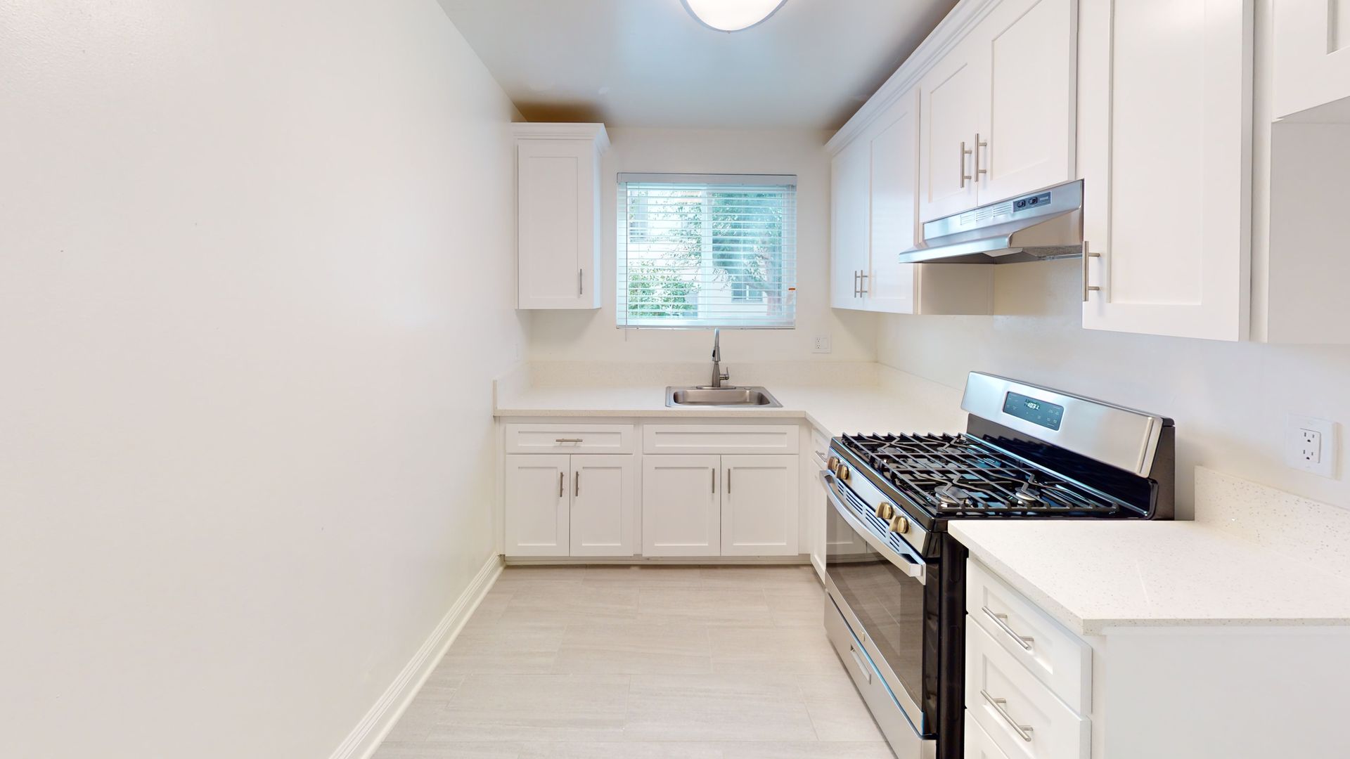 White kitchen with cabinets, stainless steel appliances, and a window.