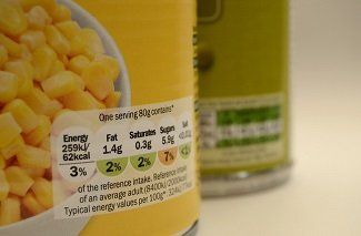 A can of corn is next to a bowl of corn.