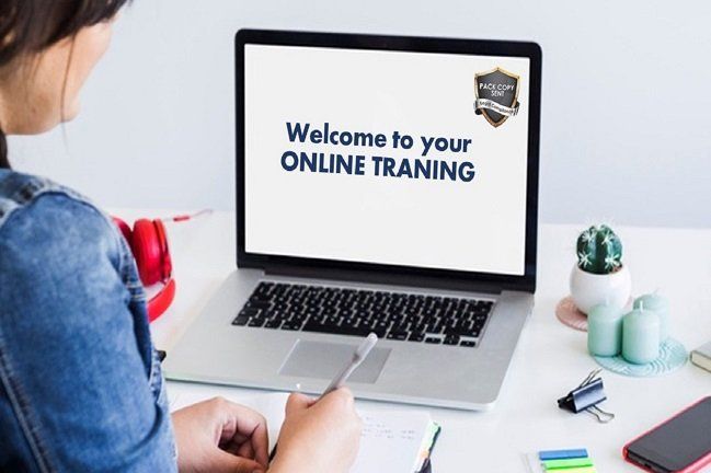 A woman is sitting at a desk in front of a laptop computer.