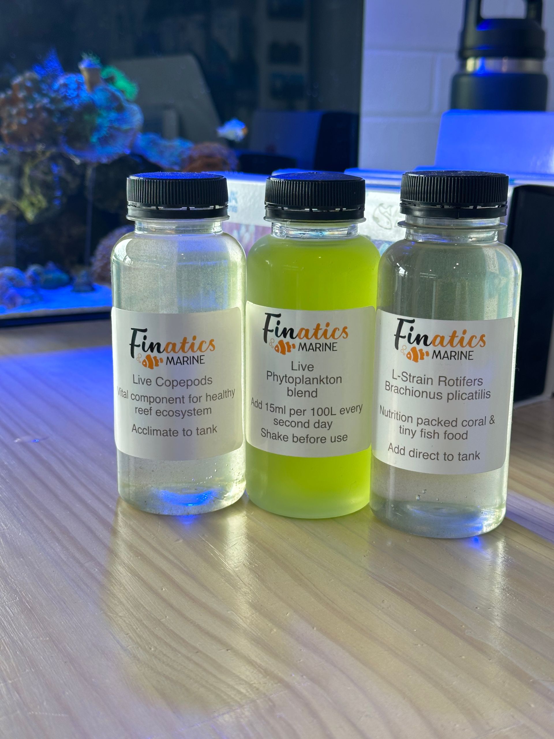 Three Bottles of Finatics Juice Sit on a Table — Finatics Marine in Macquarie, NSW