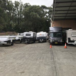 A row of rvs are parked in a parking lot.