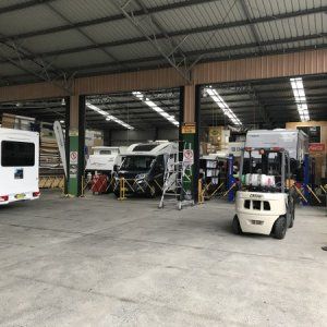 A forklift is parked in a garage next to a row of rvs.