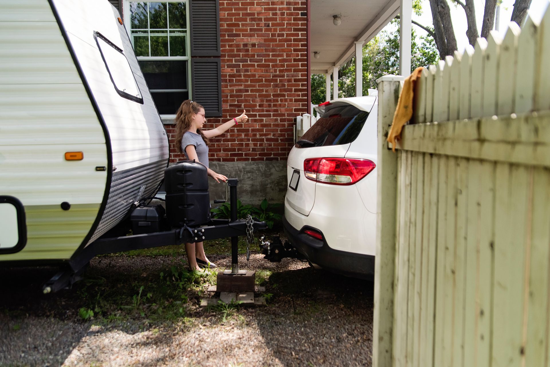 A woman is giving a thumbs up next to a trailer