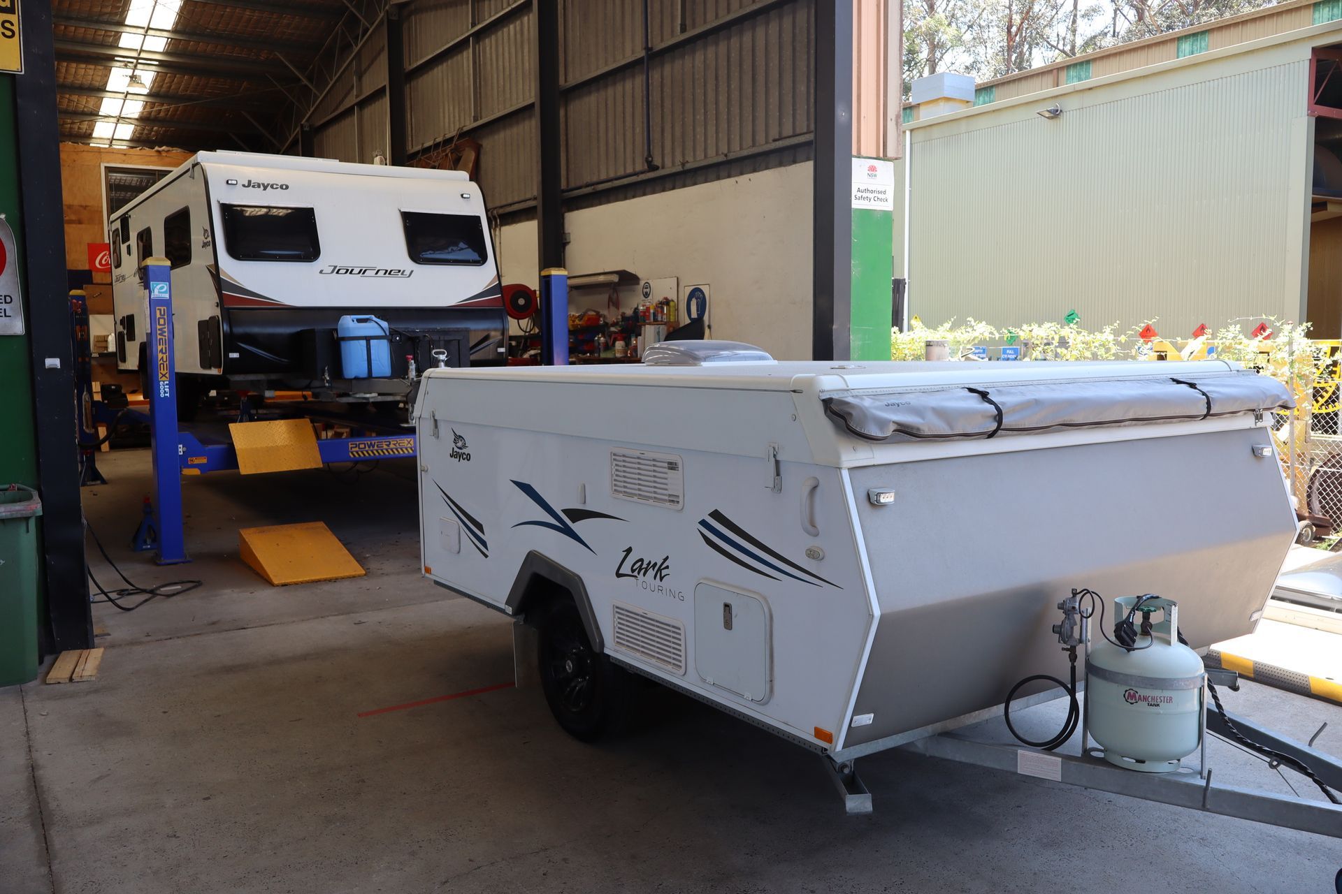 A woman is giving a thumbs up next to a trailer