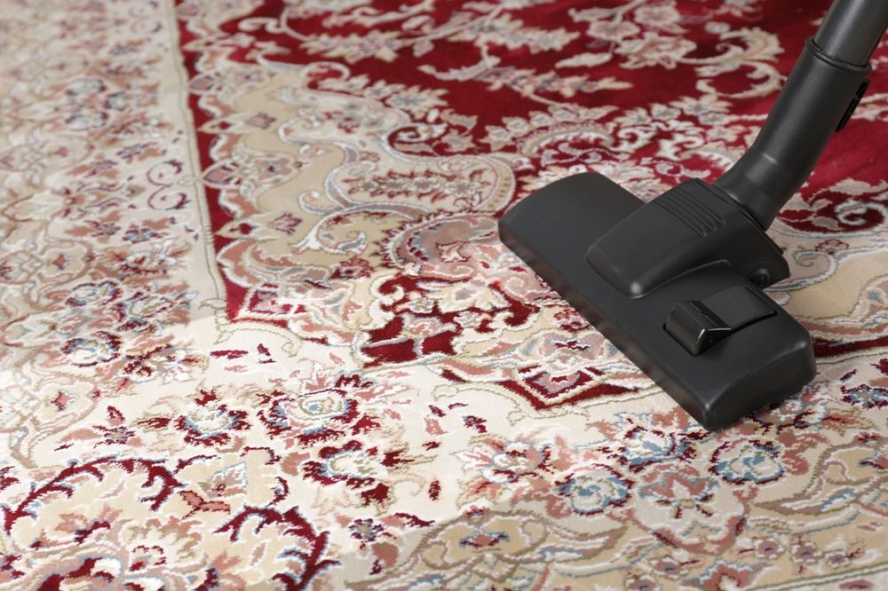 A vacuum cleaner is being used to clean a rug.