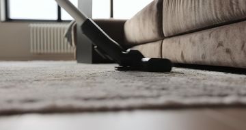 A person is using a vacuum cleaner to clean a carpet in a living room.