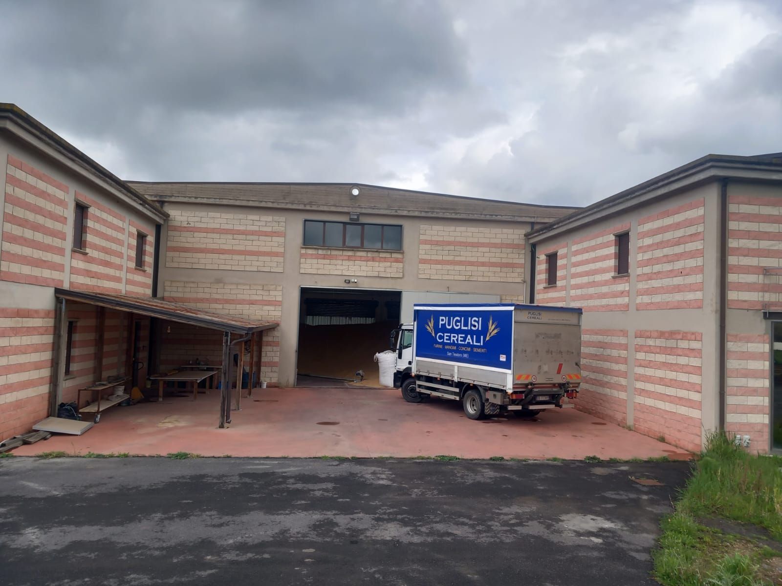 Un'autocisterna bianca utilizza un tubo pneumatico per trasportare il mangime in un grande silo bianco sopraelevato in una fattoria.