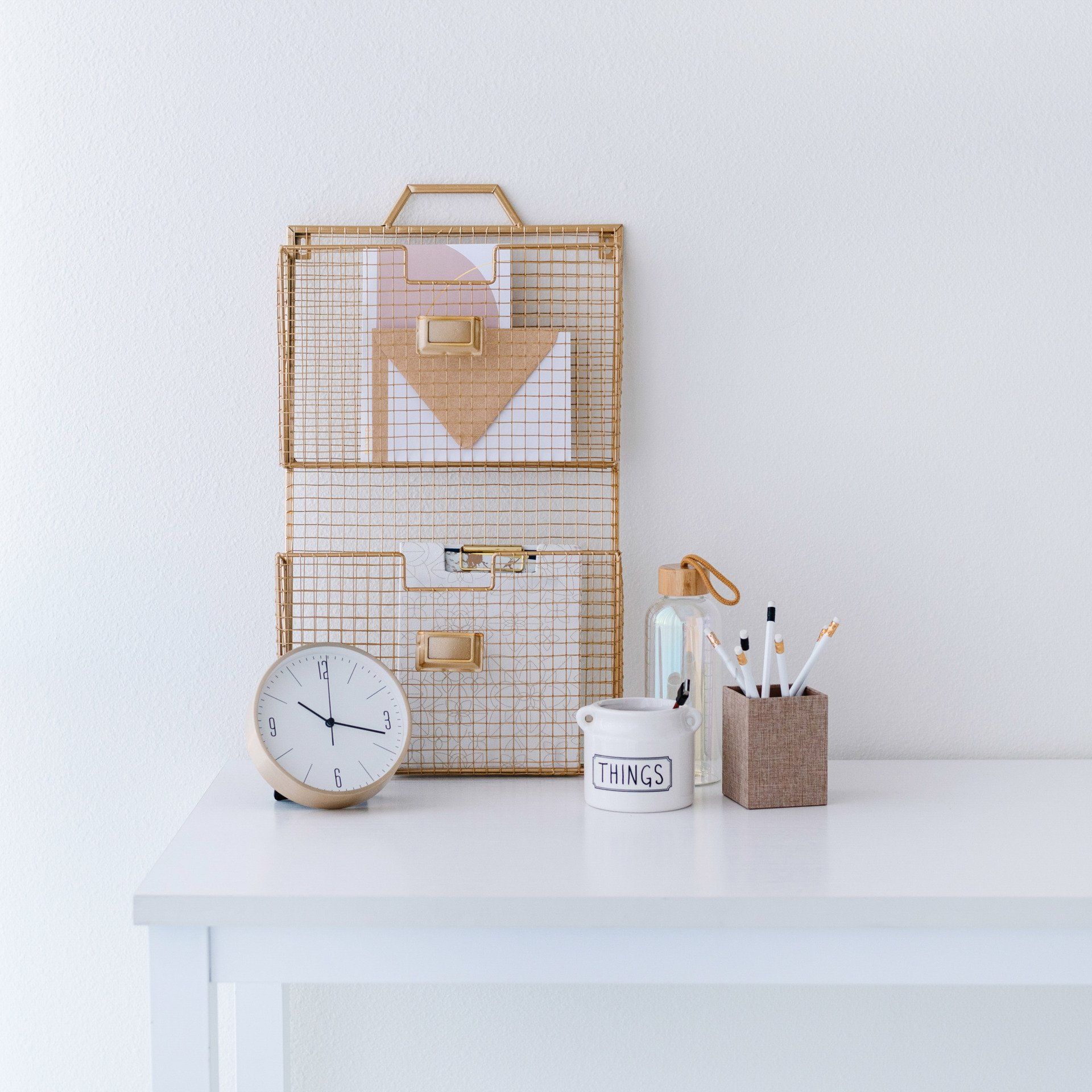 A white desk with a clock and a container that says likes