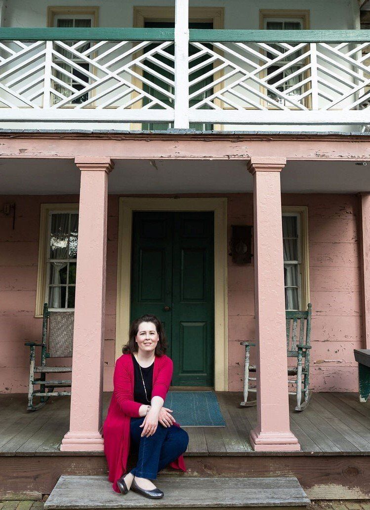 Woman in red sweater, jeans sits on porch. Primer & Scout, LLC welcomes solopreneurs, small business