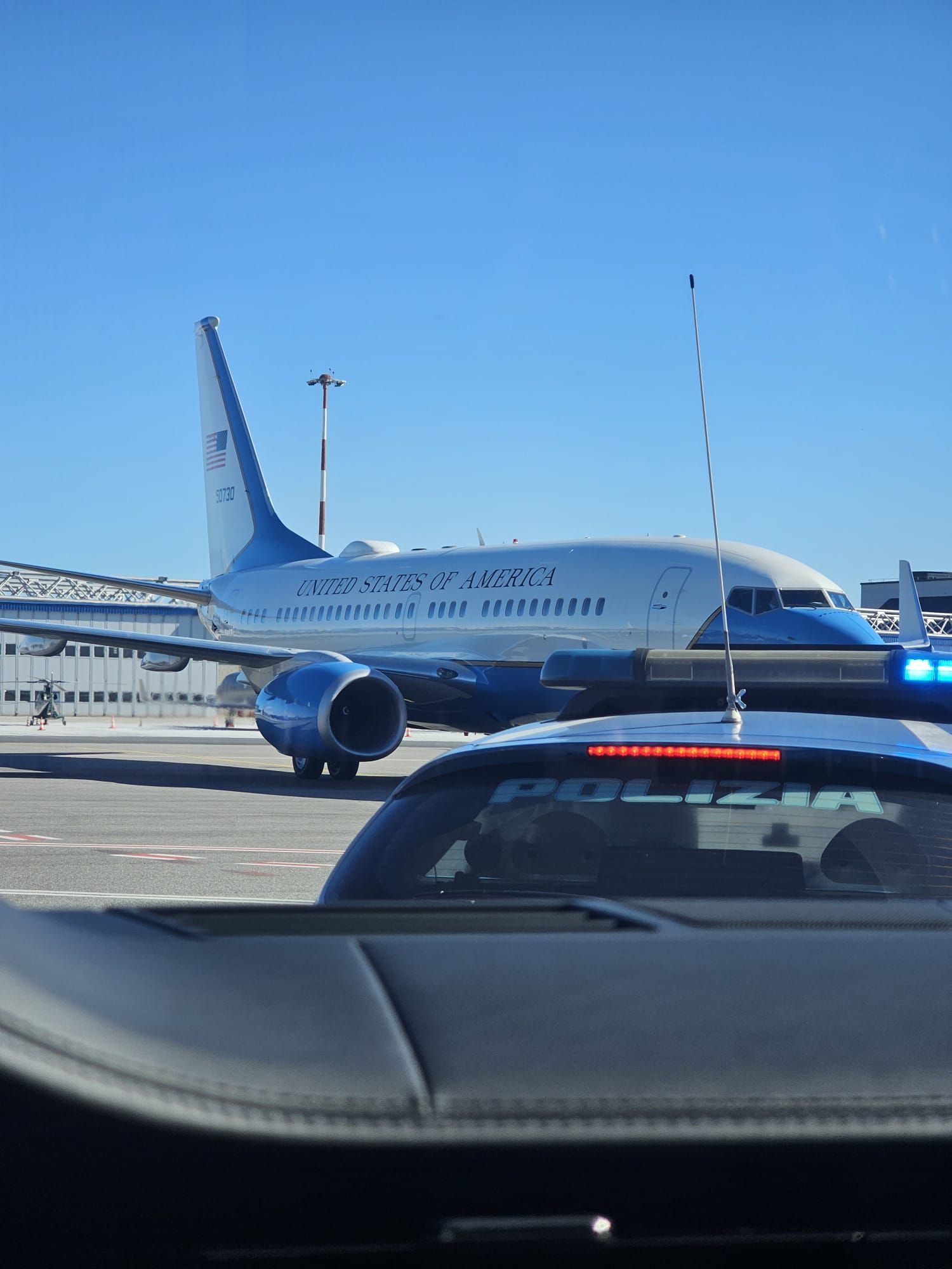 Un avion roule sur la piste à côté d'une voiture de police à l'aéroport