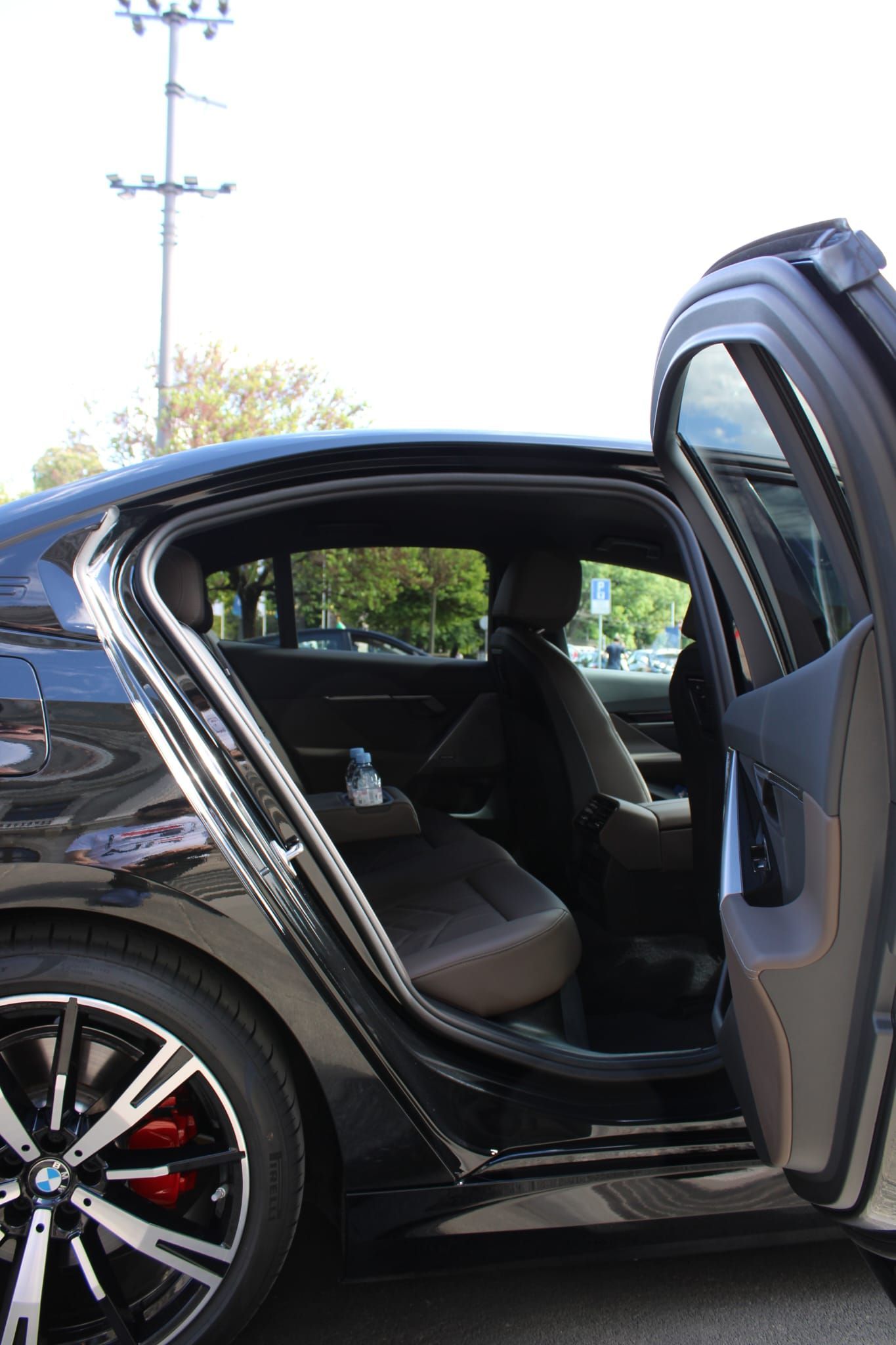 Portière ouverte révélant un intérieur en cuir noir et une banquette arrière dans une voiture de sport noire garée à l'extérieur.