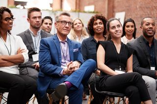 A group of people are sitting in chairs at a conference.