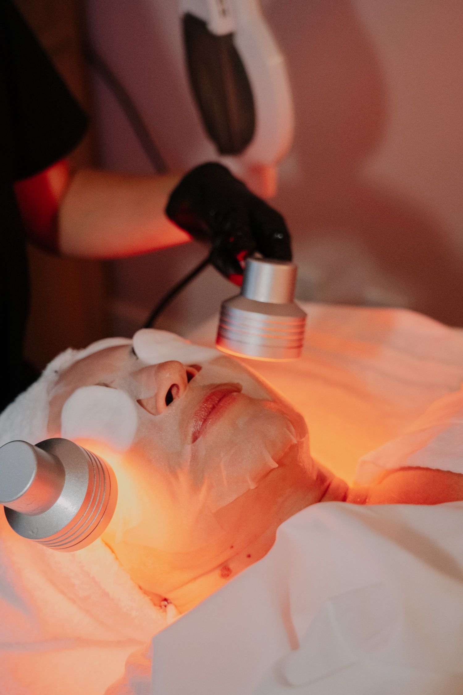 Woman undergoing facial treatment with red light therapy.