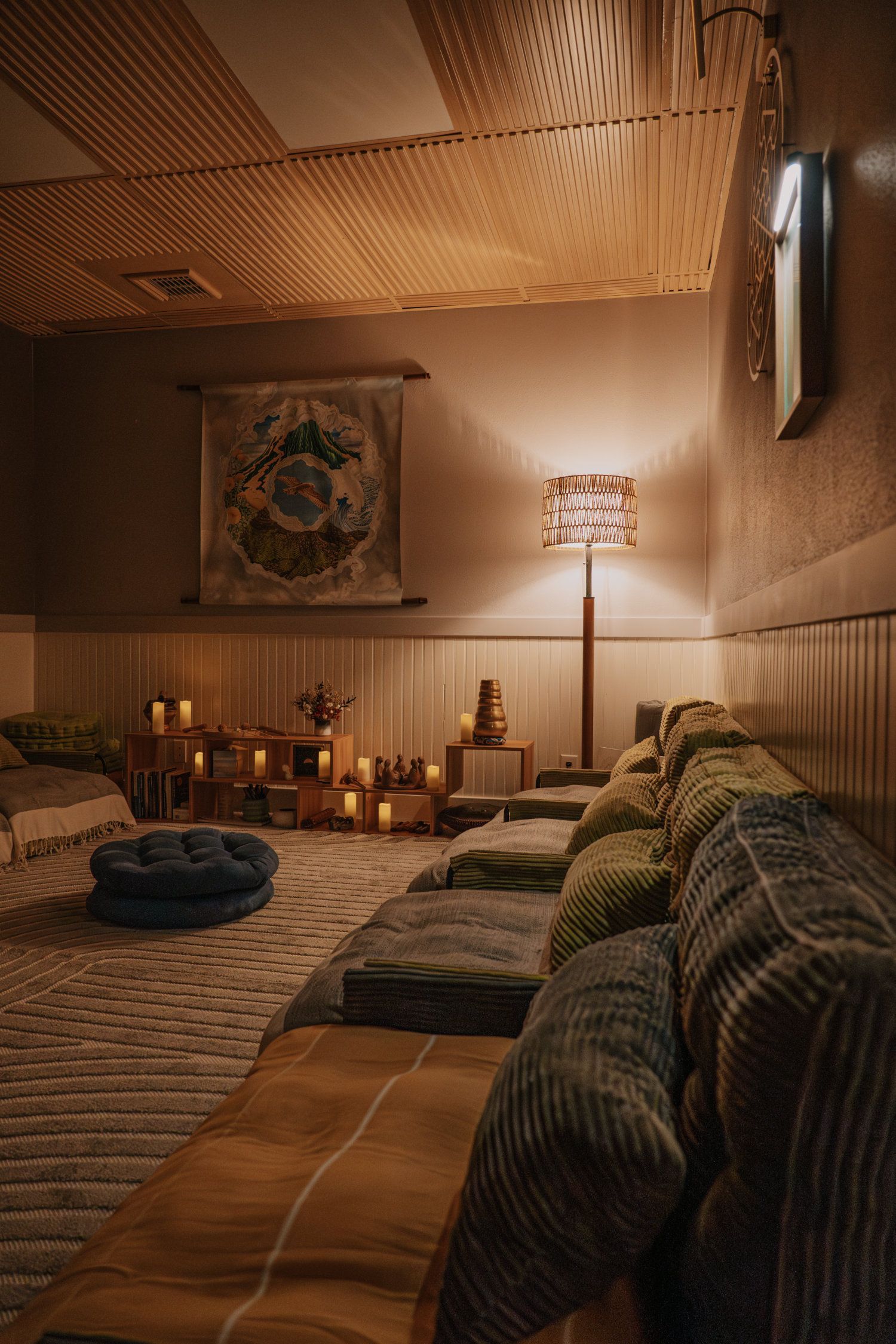 Cozy, dimly lit room with floor cushions, candles, and a macrame ceiling.